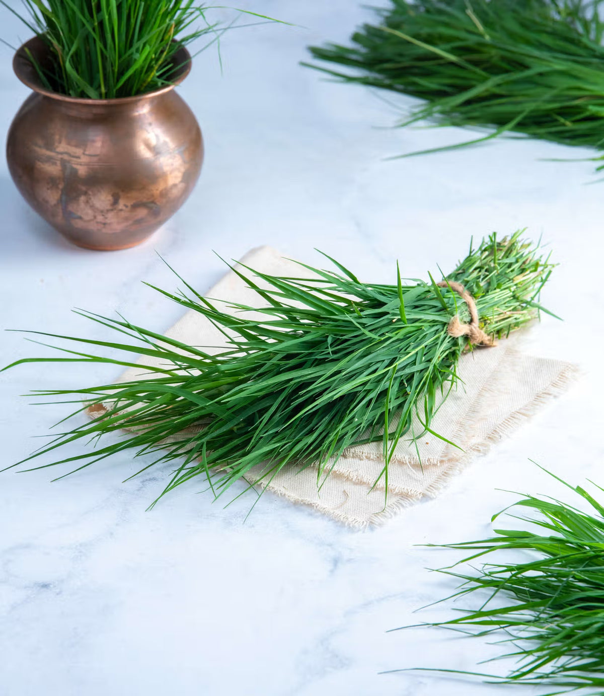 Durva grass, a traditional puja samagri ingredient, beside a copper pot