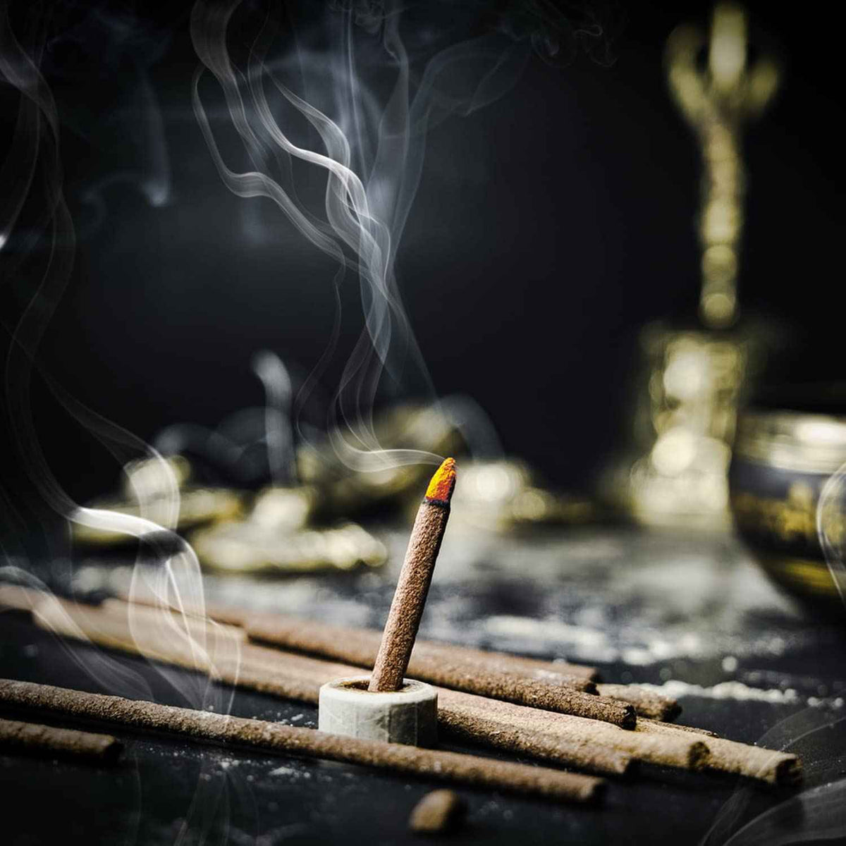 Bambooless dhoop stick lit with gentle smoke beside a brass idol