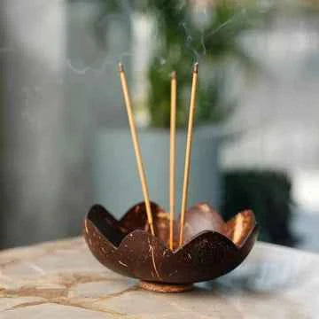 Three incense sticks lit in a coconut-shell holder